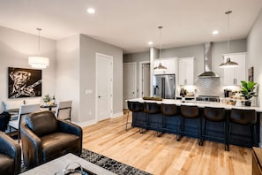 A modern kitchen with a central island, bar stools, and a dining area with a sofa and chairs. - Nashville Duo Retreat • Private Rooftops (Nashville)