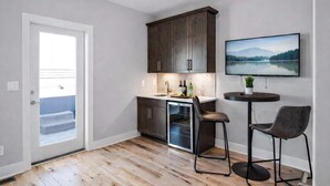 A modern kitchen with dark cabinets, a built-in oven, and a small dining area with two chairs.
