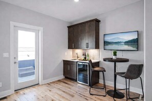 Eine moderne Küche mit dunklen Schränken, einem eingebauten Backofen und einer kleinen Essecke mit zwei Stühlen.