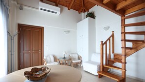 A living room with a wooden staircase, a round table with a decorative bowl, and a white sofa. - Seaside Gialova (Pylos-Nestoras)