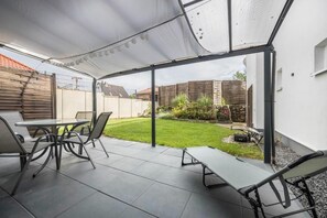 Enjoy dining or socializing in this outdoor space with a shaded table and comfortable seating.