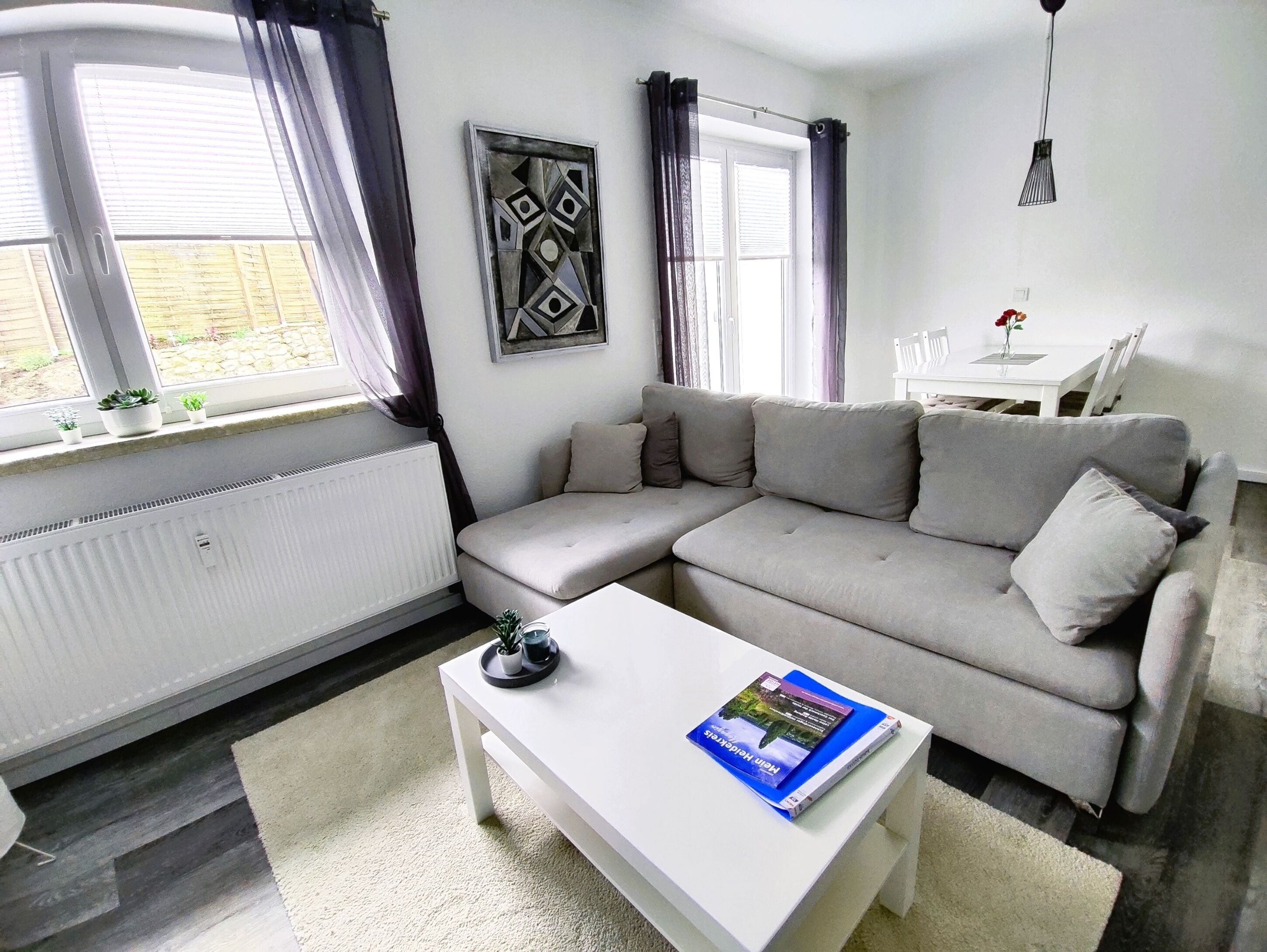 Ein modernes Wohnzimmer mit einem grauen Sofa, einem weißen Couchtisch und einem Gemälde an der Wand.