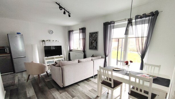 A compact living space with a sofa, dining table, and a TV. - Vacation apartment Heide I (Walsrode)
