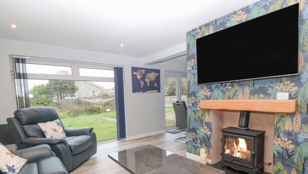 Una sala de estar moderna con un sofá de cuero, una mesa de centro de vidrio, una chimenea y un televisor grande montado en la pared.