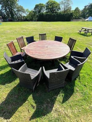 A round wooden table with wicker chairs in a grassy outdoor area. - Dukeries Retreat (Barnby Moor)