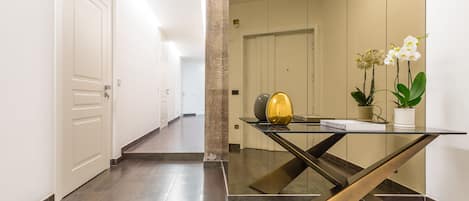 A modern hallway with a glass table, a potted plant, and a decorative vase.