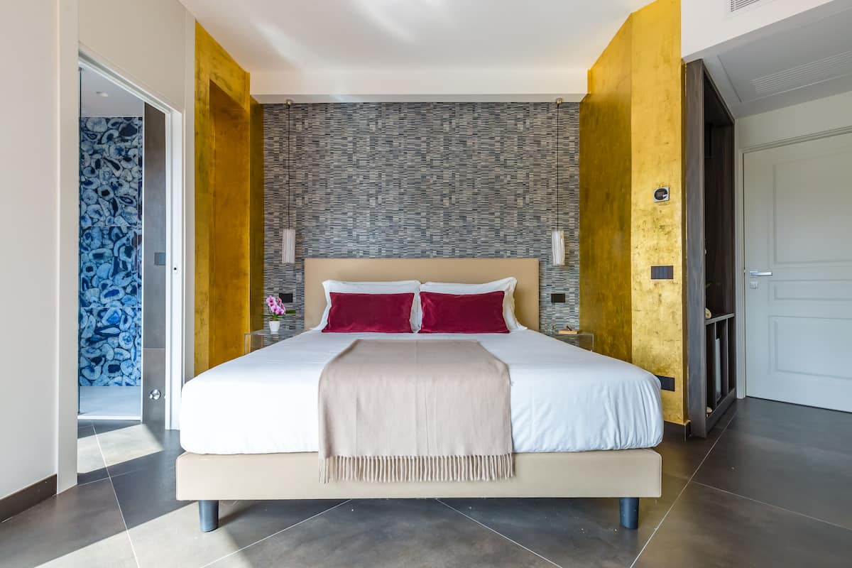 Un dormitorio moderno con una cama grande, un papel tapiz decorativo y una puerta que da a otra habitación.