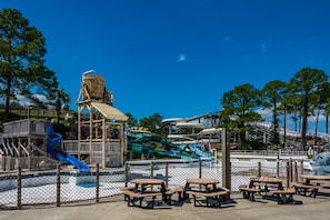 A water park with slides, picnic tables, and a wooden play structure.