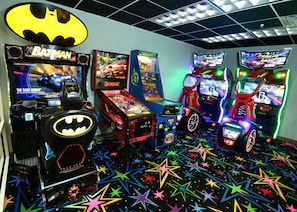 Eine Spielhalle mit verschiedenen thematischen Spielautomaten, darunter Batman und Rennspiele.