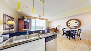 A kitchen with a built-in dishwasher, a dining area with a round table and chairs, and a large mirror on the wall.