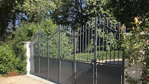 A gated area with a metal fence and a gravel path leading to a building. - Charming Burgundy vacation rental with a beautiful pool, sleeps 8—Relaxation guaranteed (Franxault)