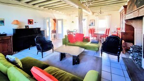 A spacious living room with a high wooden ceiling, a fireplace, and a dining area with red chairs. - Charming Burgundy vacation rental with a beautiful pool, sleeps 8—Relaxation guaranteed (Franxault)
