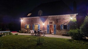 A brick house with a patio and outdoor seating area at night. - Charming Burgundy vacation rental with a beautiful pool, sleeps 8—Relaxation guaranteed (Franxault)