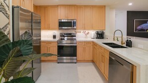 A modern kitchen with stainless steel appliances, wooden cabinets, and a marble countertop.
