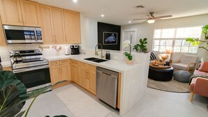 A modern kitchen with wooden cabinets, stainless steel appliances, a dishwasher, and a large window providing natural light.
