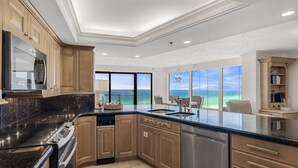 A modern kitchen with a large island, stainless steel appliances, and a view of the ocean. - Beachfront Wraparound Balcony ~ Golf Cart ~ Pool (Miramar Beach)