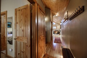Un couloir en bois avec un banc, des portes en bois et un porte-manteau fixé au mur.