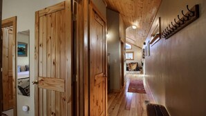 Ein Holzboden-Flur mit einer Bank, Holztüren und einem an der Wand befestigten Garderobenhaken.