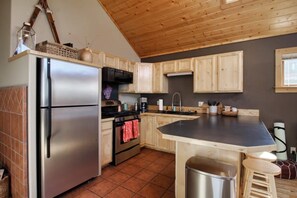 Une cuisine avec des meubles en bois, un réfrigérateur en acier inoxydable, une cuisinière et un évier.