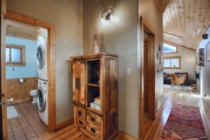 A room with a wooden cabinet, a washing machine, and a ceiling light. - The Little Lodge Leadville — 2BR with Hot Tub, Pet-OK, 1.5 Blocks to Harrison (Leadville)