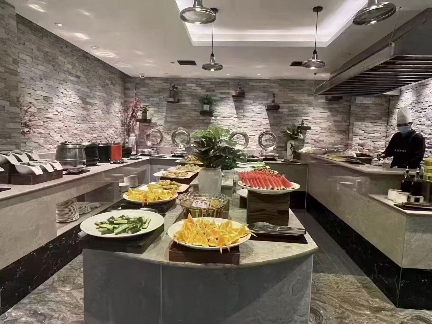 Una mesa de buffet con diferentes alimentos y un chef preparándolos.