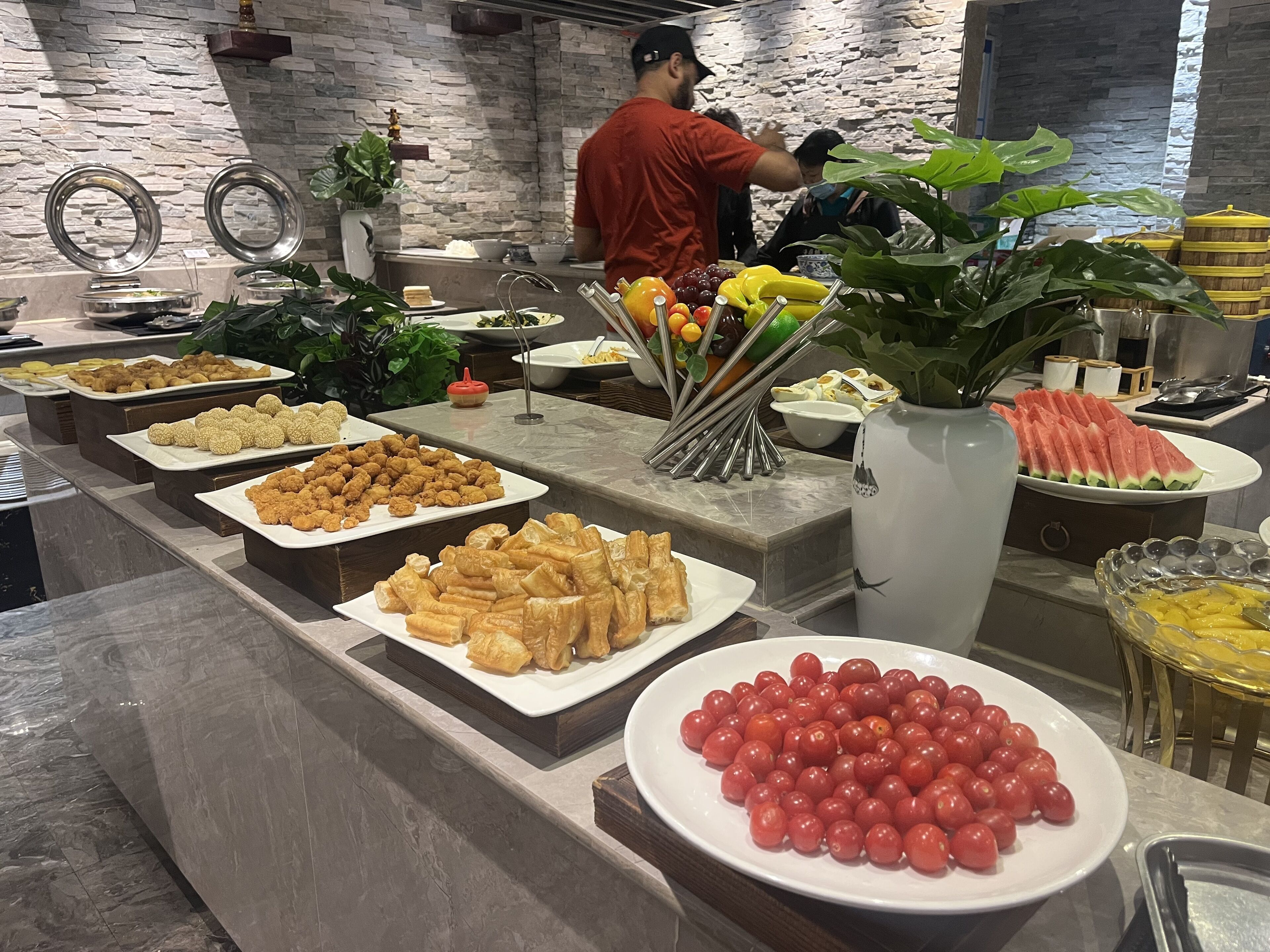 A buffet with various food items including fried snacks, pastries, and fresh fruits.