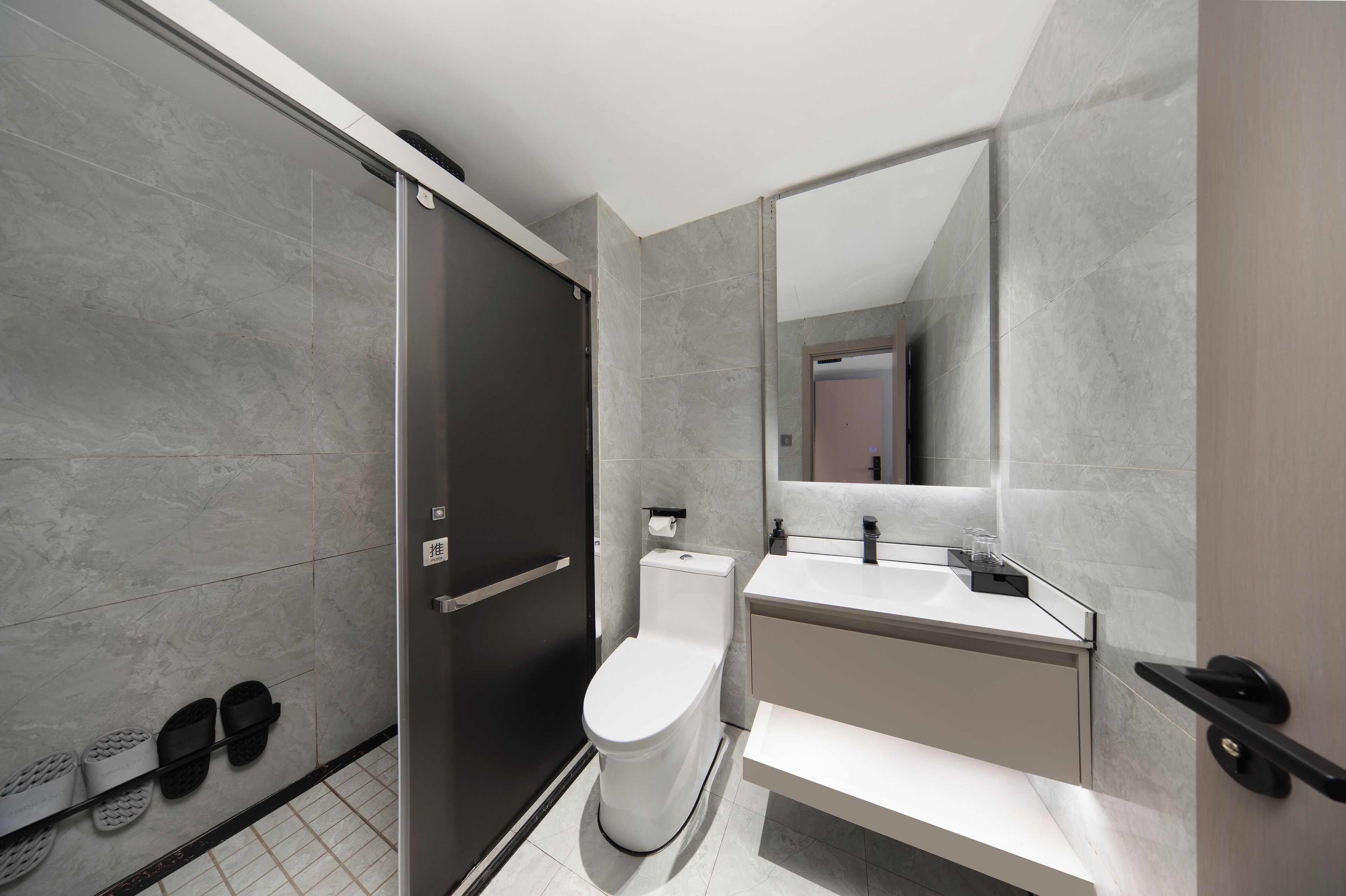 A modern bathroom with a walk-in shower, toilet, and sink.
