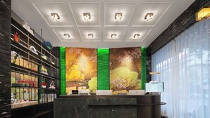 A reception area with a marble counter, shelves with decorative items, a large wall mural, and a digital display. - Yiwu  Manting City Hotel (Jinhua)
