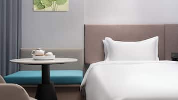 Une chambre d’hôtel avec un lit, une table ronde avec une théière et des tasses, un banc bleu rembourré et une œuvre d’art accrochée au mur.