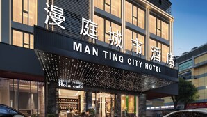 Un hotel con una fachada moderna, una cafetería llamada "Holo cafe" en la entrada, y un cartel que indica "MAN TING CITY HOTEL".
