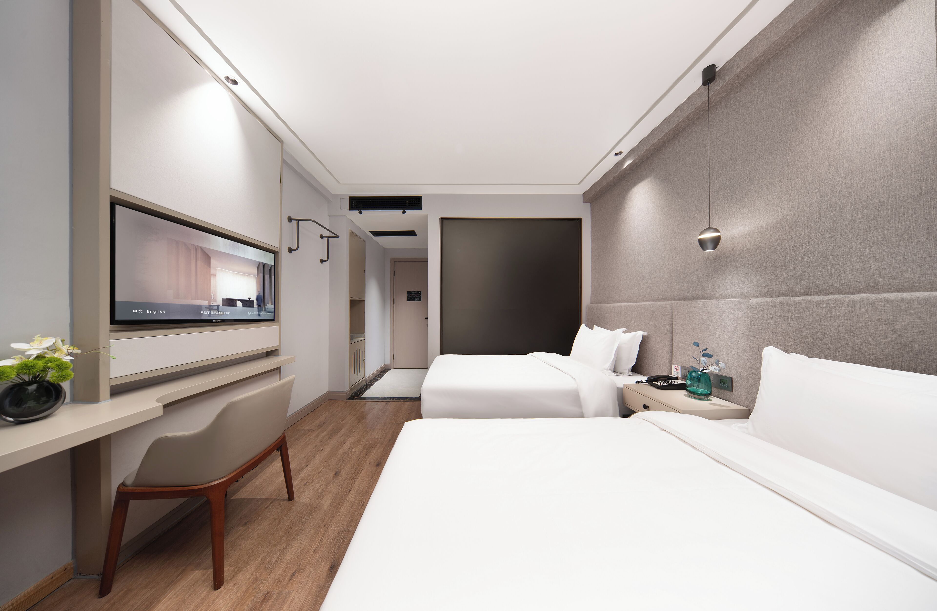 Een moderne hotelkamer met een bed, nachtkastje, televisie en een bureau met stoel.