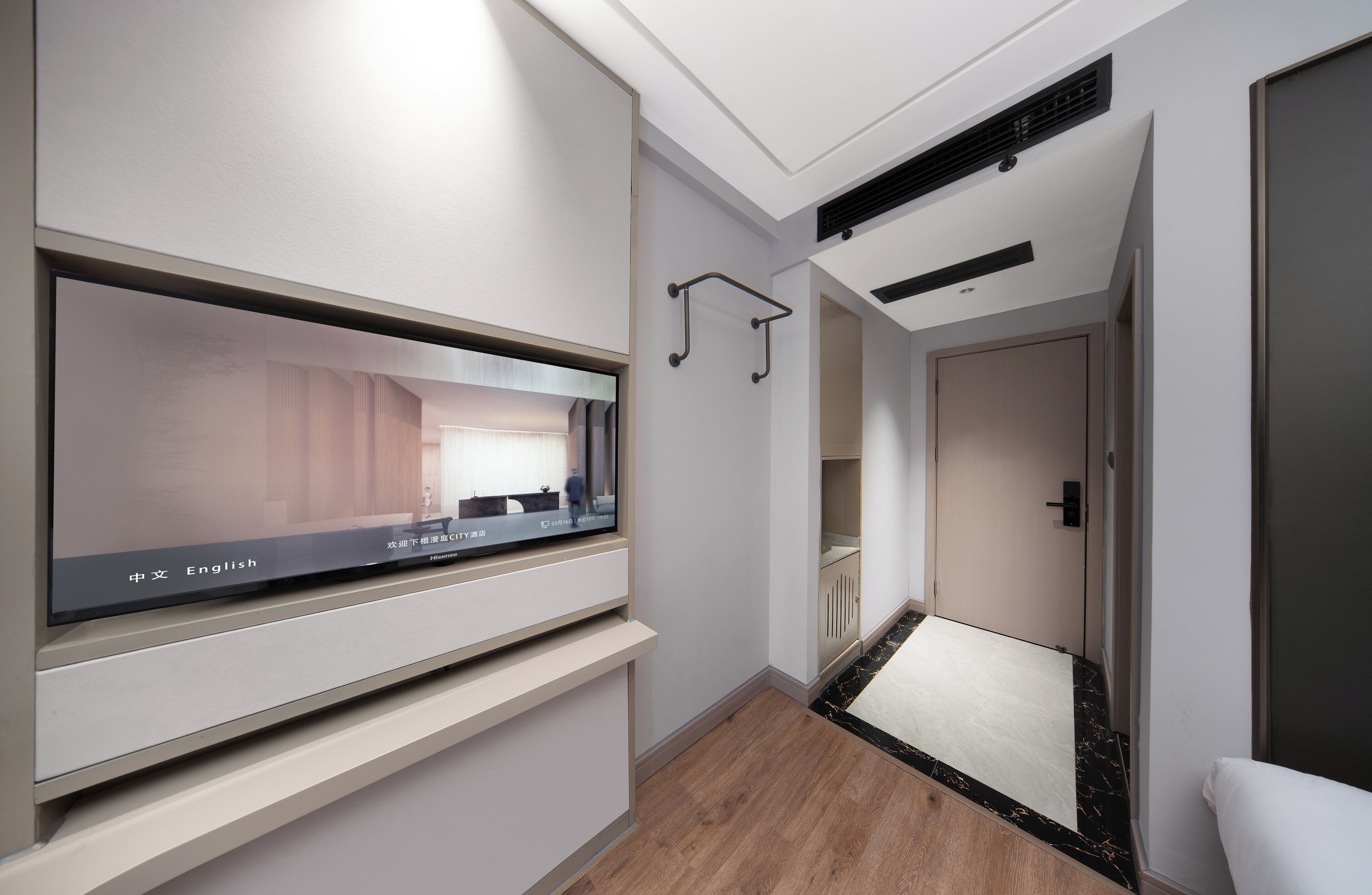 A modern hotel room with a large flat-screen TV, a walk-in closet, and a compact bathroom.