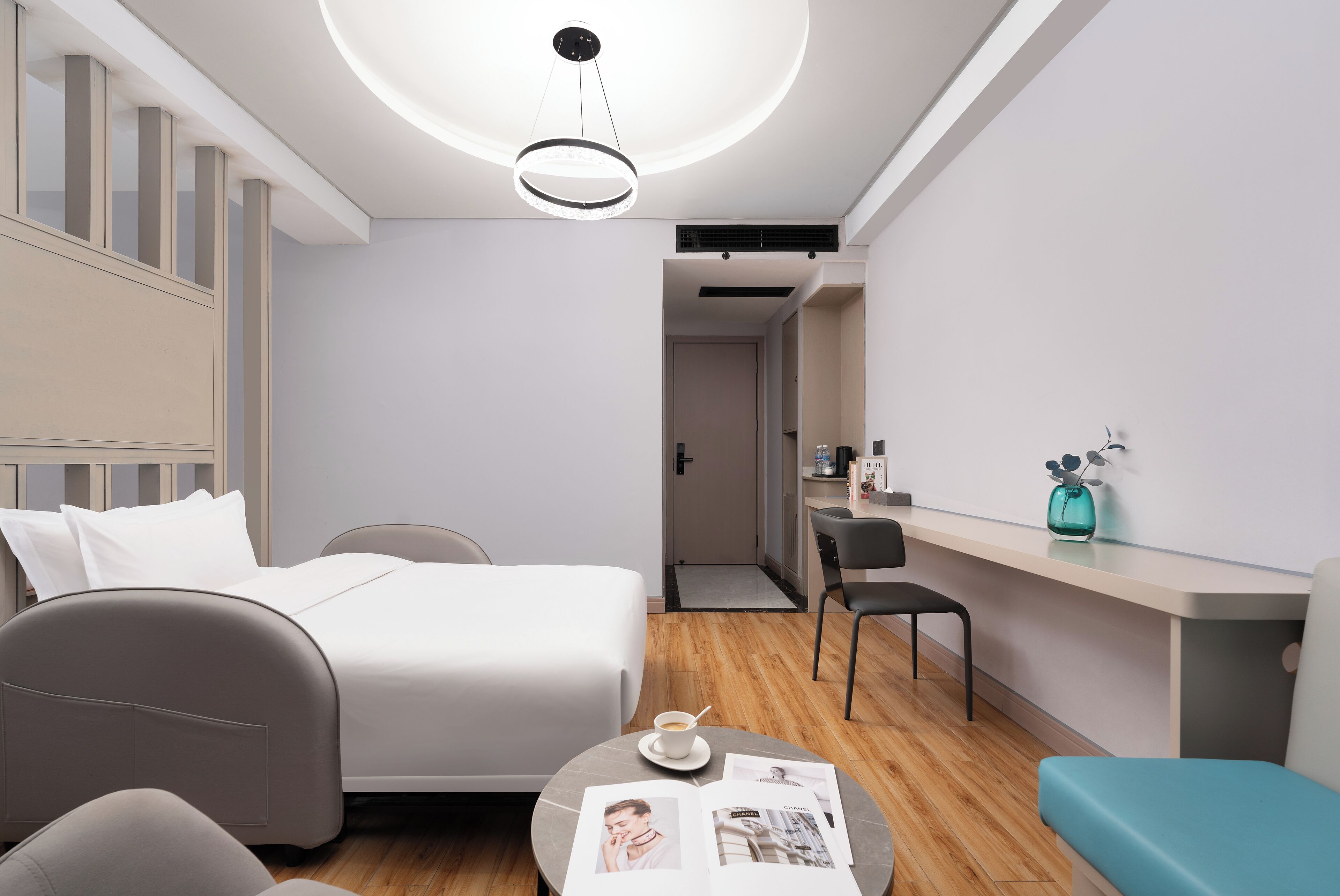 Una habitación de hotel moderna con cama, escritorio, silla, mesa de centro y una revista.