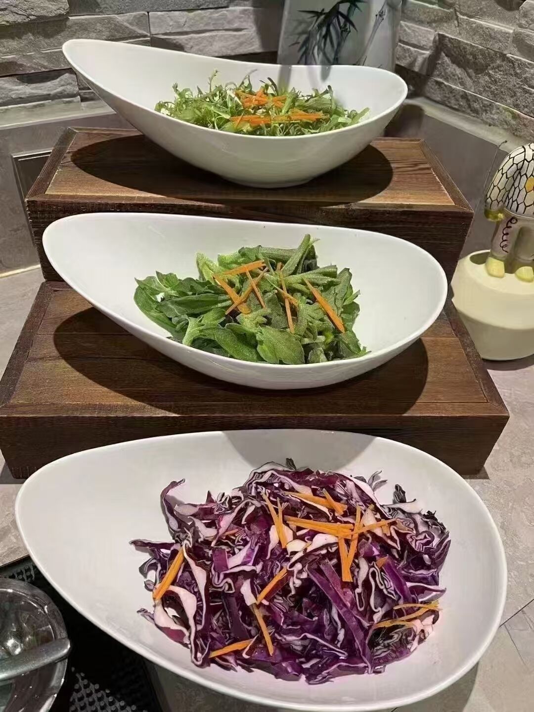 Tres ensaladas en tazones blancos sobre tablas de madera.