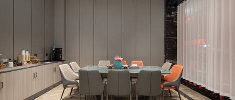 A modern dining area with a marble table, grey chairs, and a vase of flowers.
