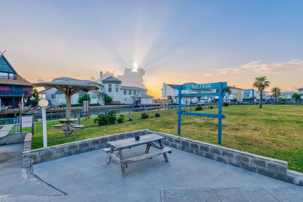 A beachfront condominium complex with a clear view of the ocean, a picnic table, and a sign for Baytree Condominiums.