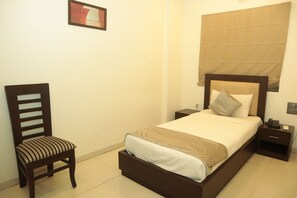 A neatly arranged bedroom with a bed, bedside tables, a chair, and a framed picture on the wall.