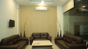 A modern living room with two brown leather sofas, a central coffee table, and two tall vases with branches. - K Plus Comforts (Karwar)