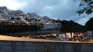 A coastal resort with multiple white buildings, palm trees, and a landscaped area with lounge chairs. - Xeresa del Monte 85 Only Families! (Xeresa)