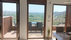 A dining area with a table set for two, a view of a balcony with a railing, and a television mounted on the wall. - Xeresa del Monte 85 Only Families! (Xeresa)