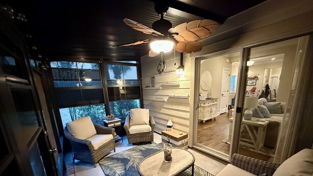 Un espace extérieur accueillant, aménagé avec des meubles en osier et doté d’un ventilateur de plafond, offrant une vue panoramique.