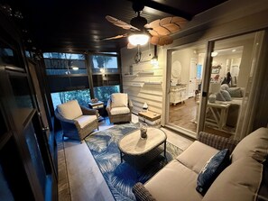 A cozy outdoor seating area with wicker furniture and a ceiling fan, overlooking a scenic view.