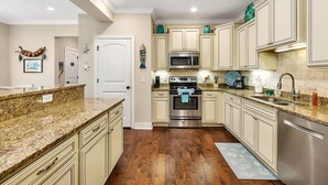 Une cuisine avec un plancher en bois, un four en acier inoxydable, un four à micro-ondes et des armoires de couleur claire.