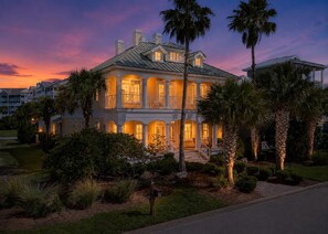A large, two-story building with a balcony, surrounded by palm trees and well-maintained landscaping.