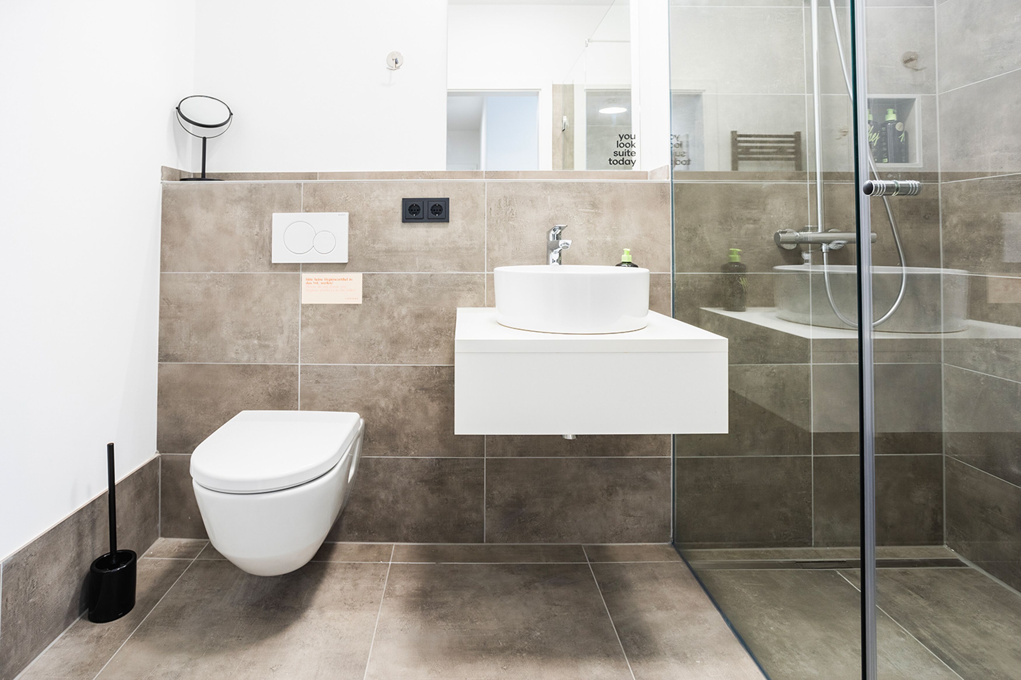 A modern bathroom with a toilet, sink, and shower.