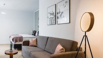 Una sala moderna con un sofá, una lámpara de pie y una cama al fondo.