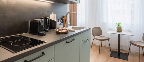 Una cocina moderna con estufa integrada, cafetera y comedor con mesa y sillas.