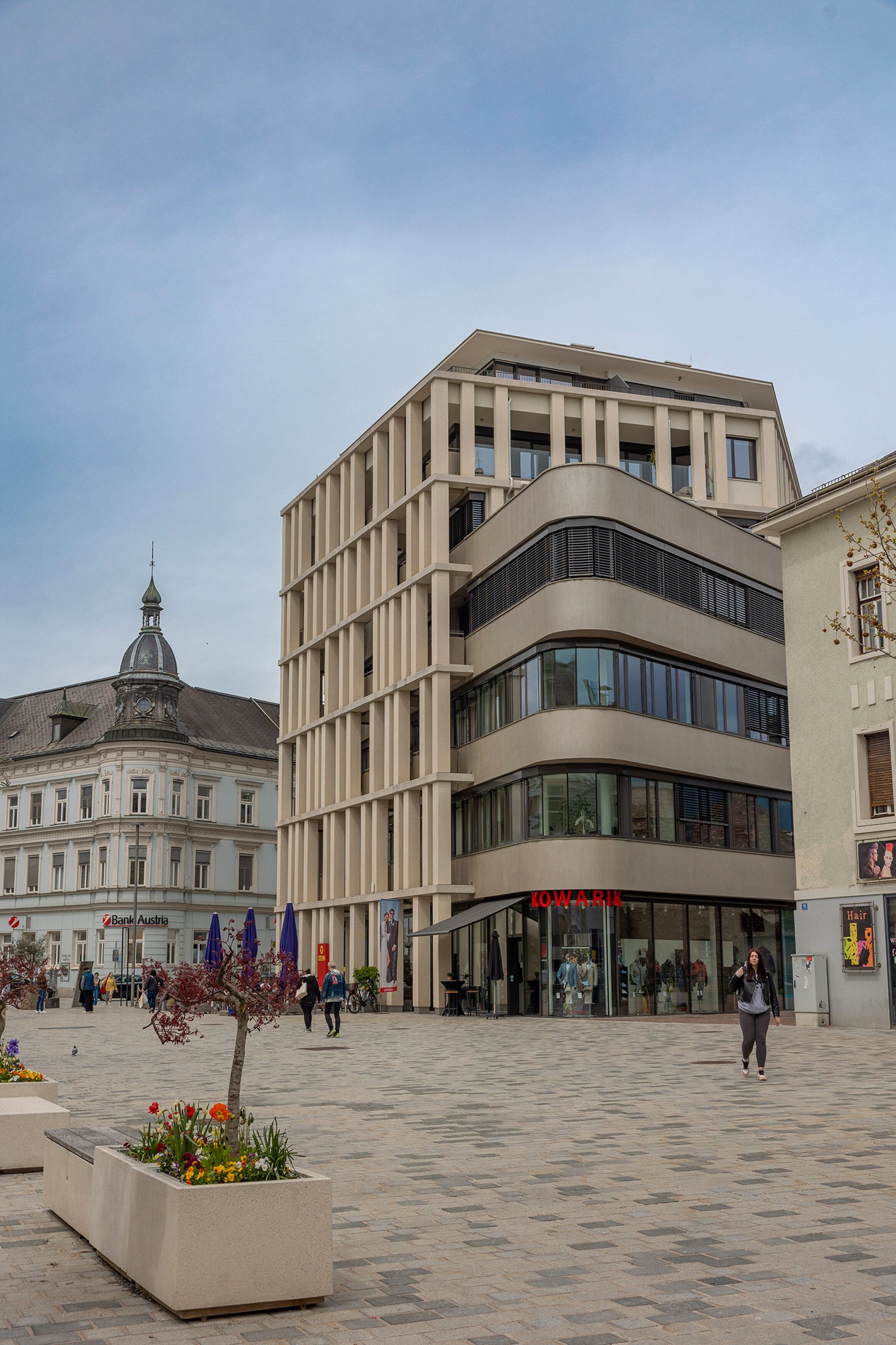A modern building with a curved facade, large windows, and a visible storefront with signage.