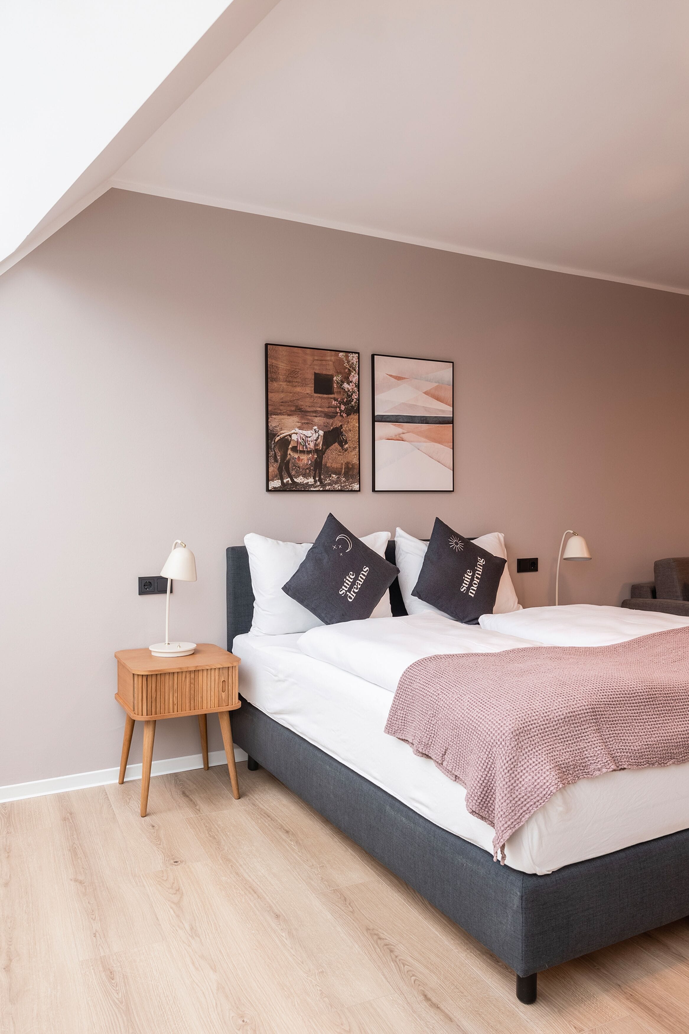 A bedroom with a bed, bedside tables, and artwork on the wall.