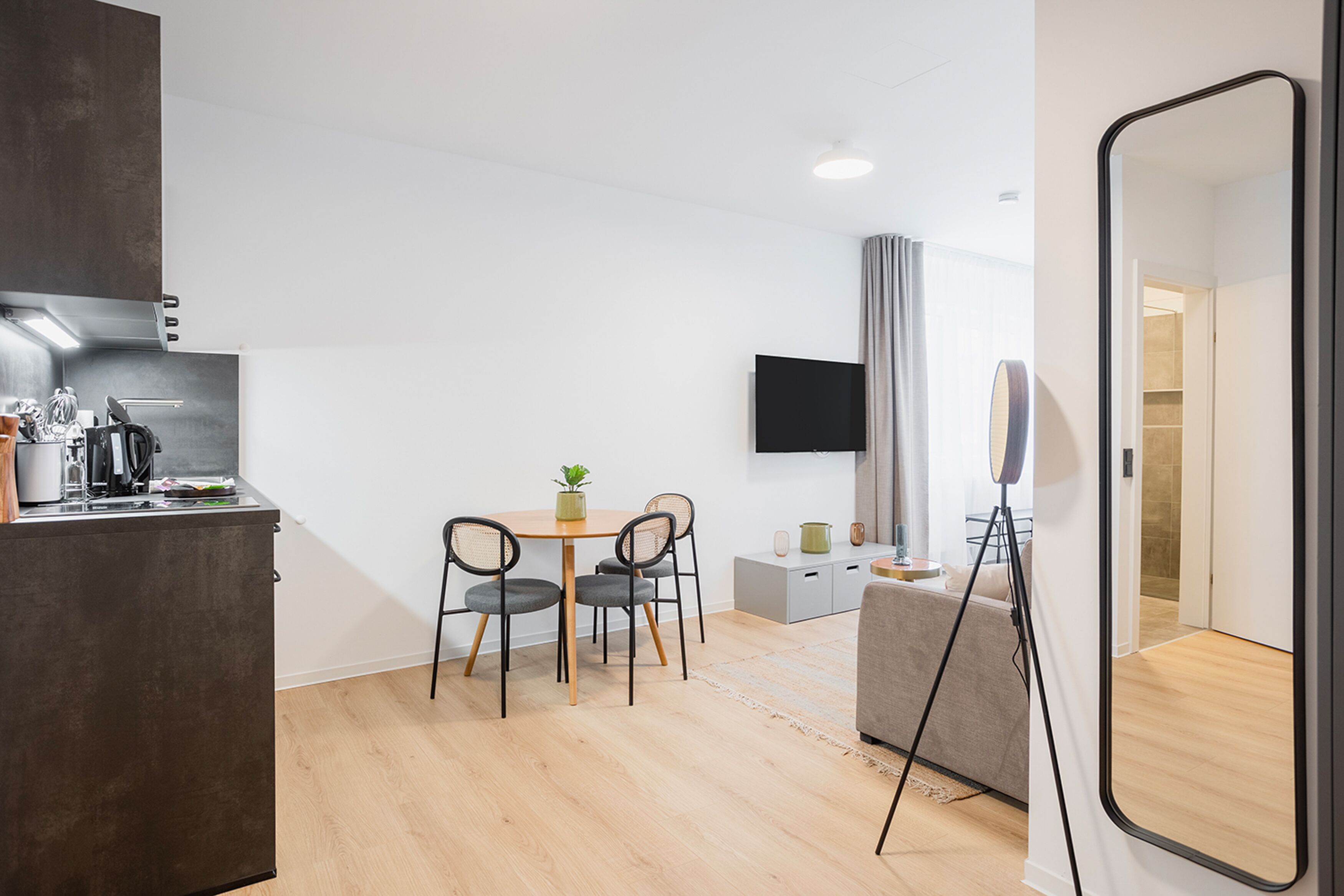 A modern kitchen with a dining area, a flat-screen TV, and a large mirror.